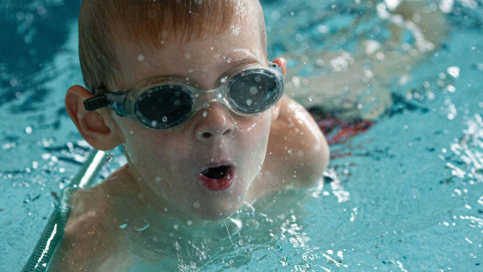 Foto de un niño en una piscina con gafas de bucear