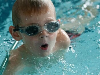 Foto de un niño en una piscina con gafas de bucear