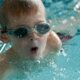 Foto de un niño en una piscina con gafas de bucear